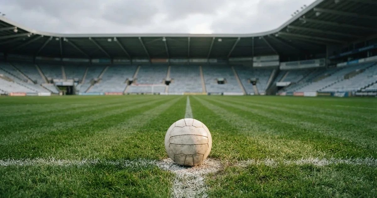 Ein Fussball liegt auf dem Anstosspunkt eines frisch gemähten Rasens, dahinter eine grosse Tribüne unter bewölktem Himmel