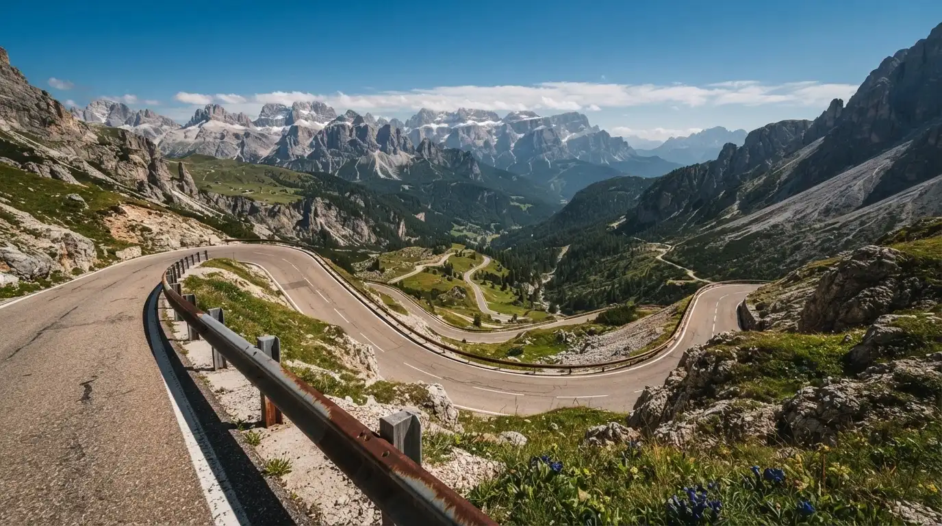 Eine Passstrasse mit Leitplanke windet sich an einem klaren Tag durch eine Berglandschaft.