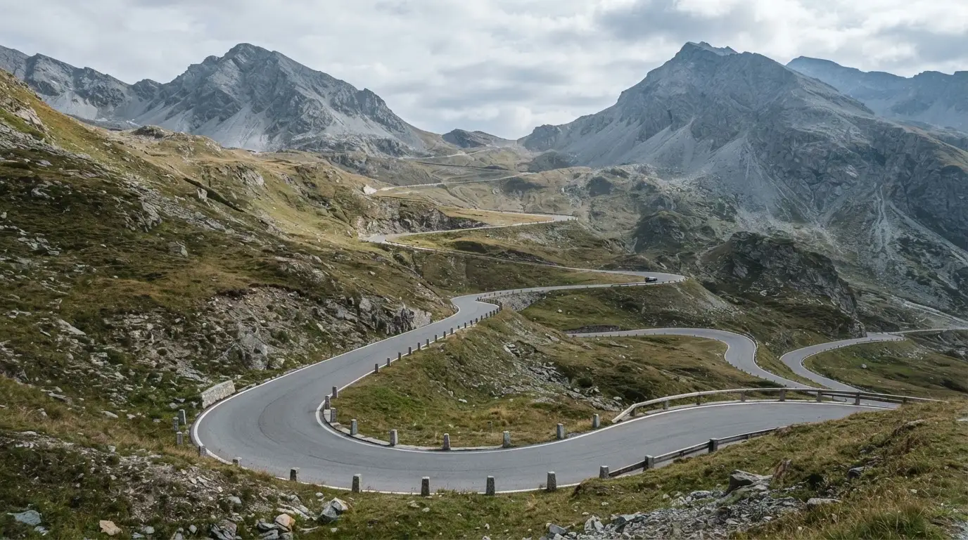Eine Passstrasse zieht sich in Kehren einen Alpenhang hinauf, kein Fahrzeug ist zu sehen.